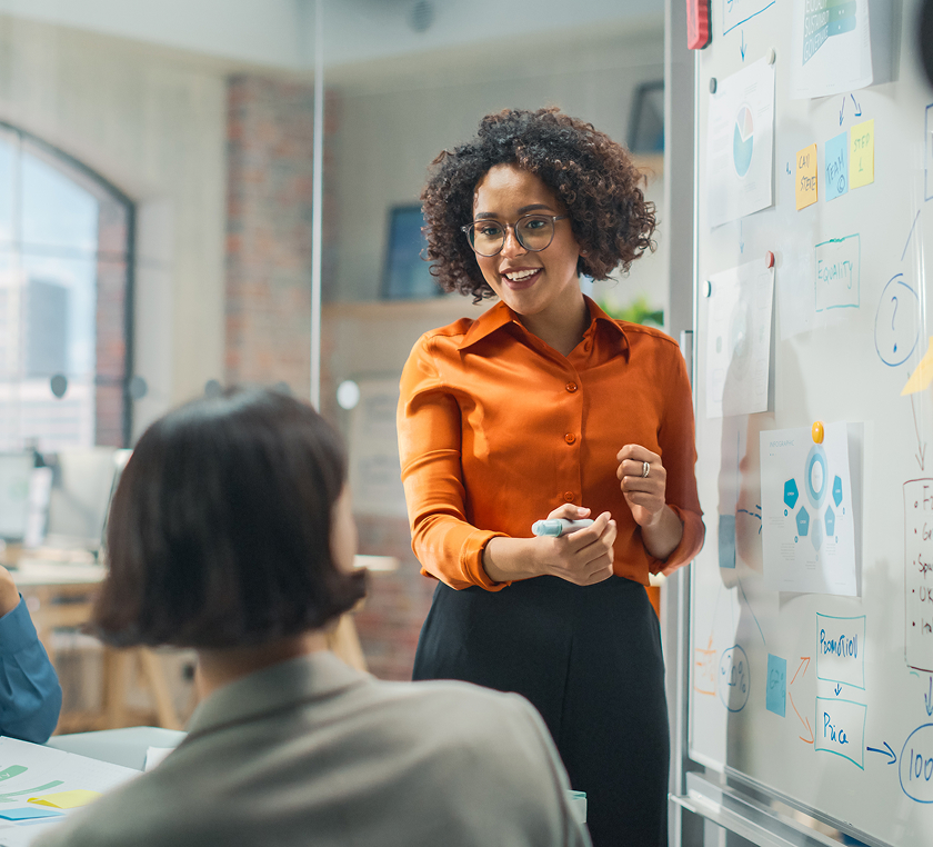 Photo of woman in an office presenting to her peers