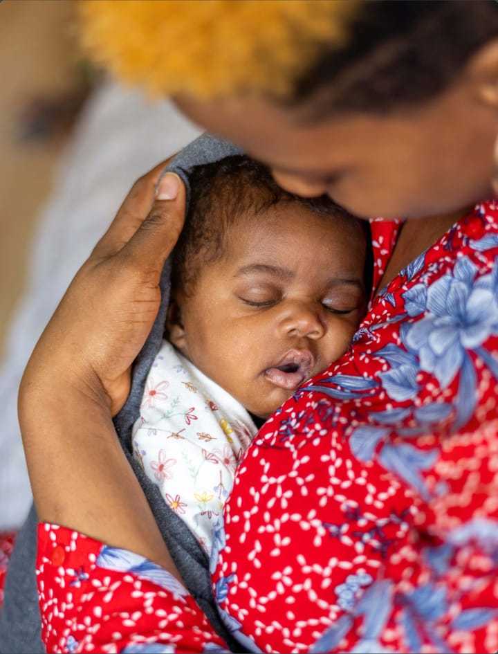 An african american woman holding her newborn child.